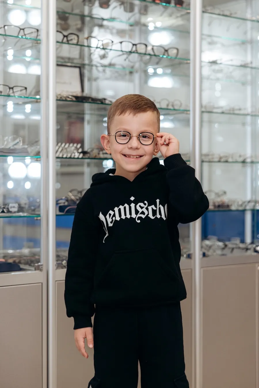 Хлопчик приміряє окуляри у відділі оптики